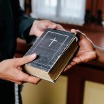Close-up of hands exchanging a Bible, symbolizing religious connection and faith.