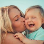 woman in teal shirt carrying girl in teal shirt